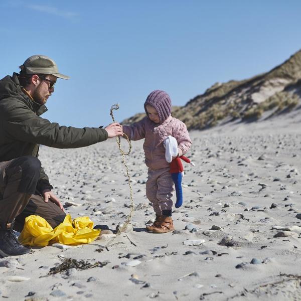 Far og datter samler affald på stranden
